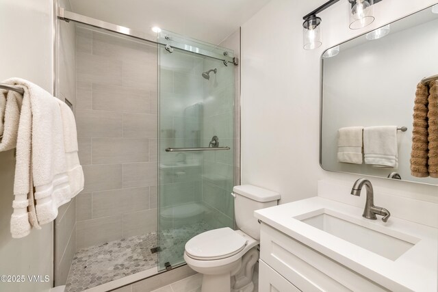 full bath with a stall shower, toilet, and vanity