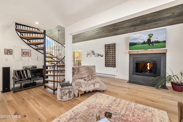 living area with baseboard heating, stairway, wood finished floors, a fireplace with flush hearth, and recessed lighting