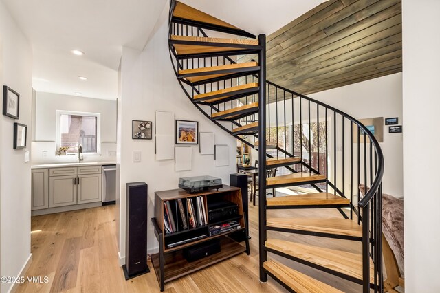 stairs featuring wood finished floors and recessed lighting