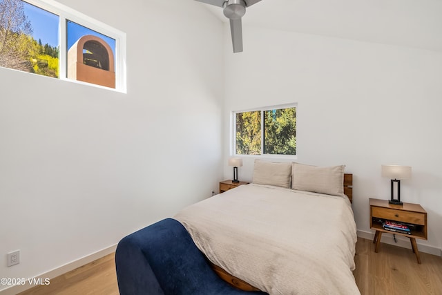bedroom with light wood-type flooring, high vaulted ceiling, and baseboards