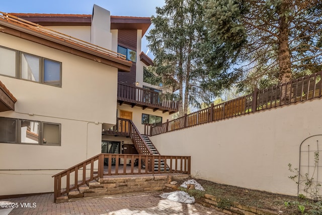 view of property exterior featuring stucco siding, stairway, and fence