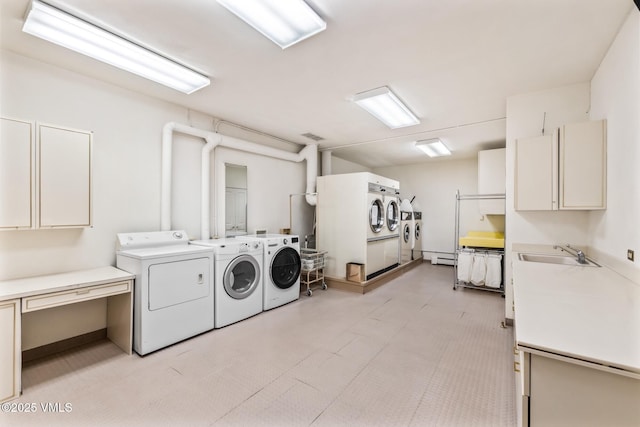 laundry room with a sink, cabinet space, a baseboard heating unit, and washer and clothes dryer