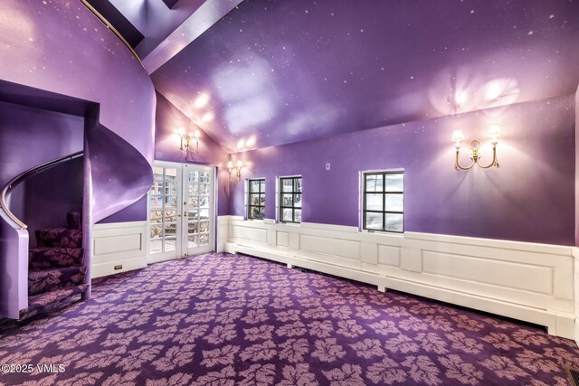 home theater room featuring carpet flooring, wainscoting, french doors, and vaulted ceiling