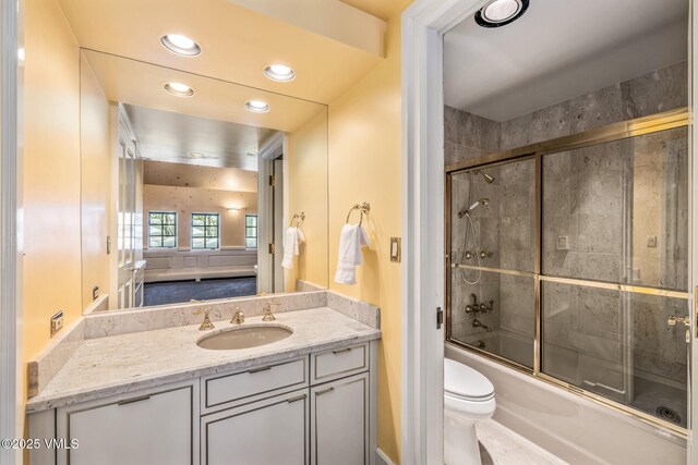 bathroom featuring combined bath / shower with glass door, recessed lighting, toilet, and vanity