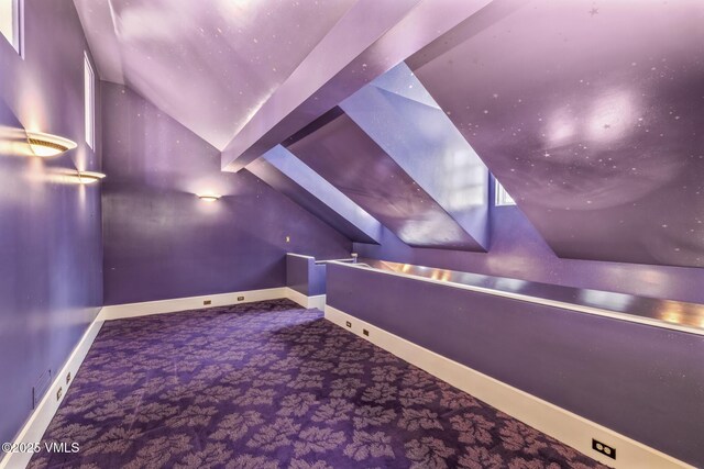 carpeted cinema room featuring baseboards and lofted ceiling