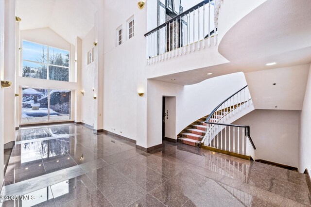 interior space featuring baseboards, granite finish floor, recessed lighting, stairs, and a towering ceiling