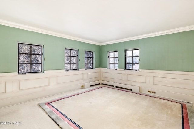 empty room featuring ornamental molding, carpet, and wainscoting