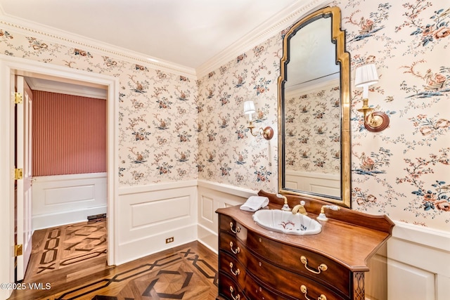 bathroom featuring a decorative wall, vanity, wainscoting, and wallpapered walls