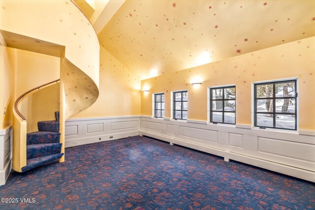 bonus room with carpet flooring, stairway, and a wainscoted wall