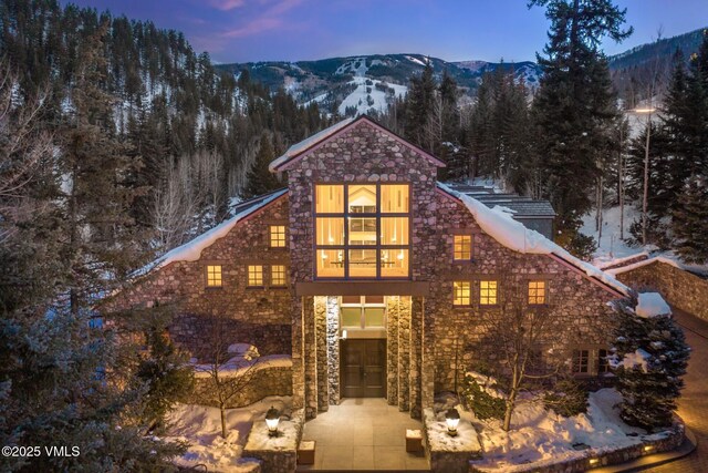 view of front of home with stone siding, a mountain view, and a wooded view