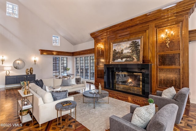 living area with high vaulted ceiling and a glass covered fireplace