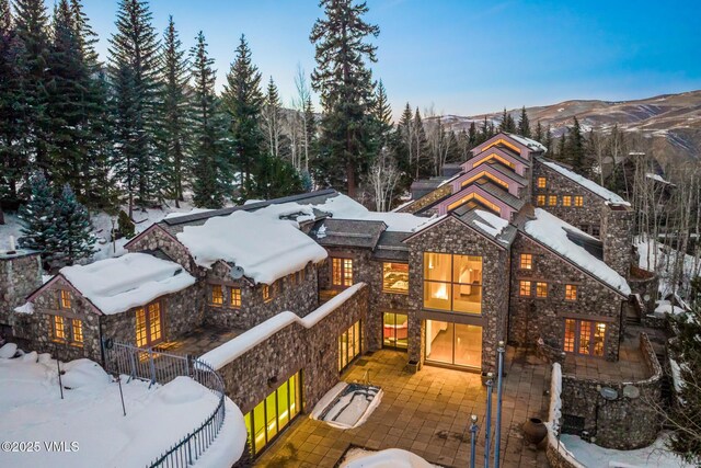 exterior space with a patio, a mountain view, fence, and stone siding