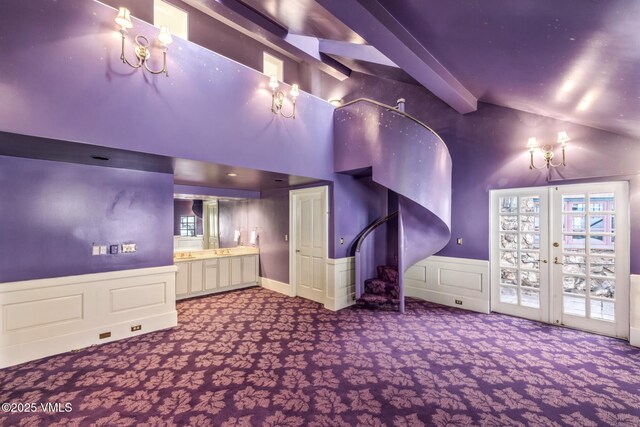 interior space with lofted ceiling with beams, french doors, wainscoting, and a decorative wall