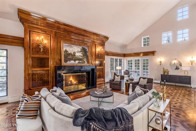 living room featuring baseboards, high vaulted ceiling, and a glass covered fireplace