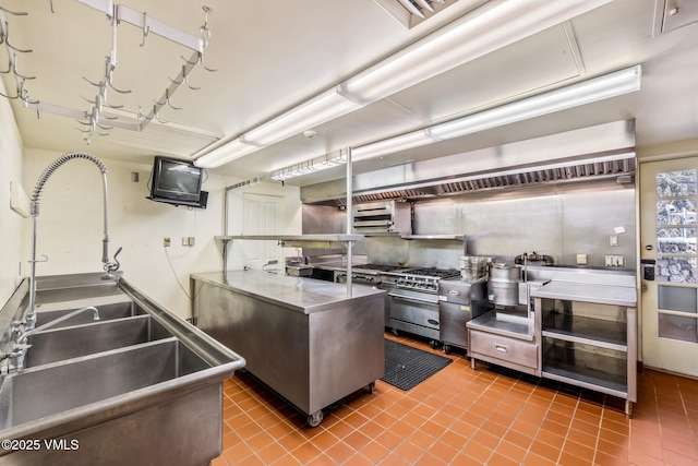 kitchen featuring tile patterned floors, high end stainless steel range oven, stainless steel countertops, and a sink