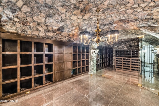 wine cellar featuring a notable chandelier and granite finish floor