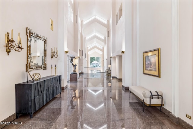 entrance foyer with baseboards, a high ceiling, and granite finish floor