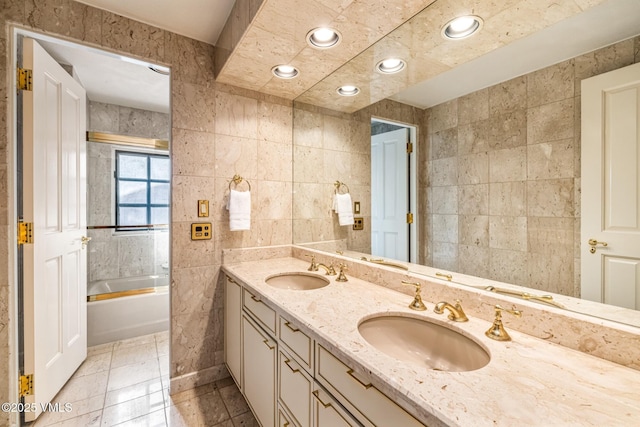 bathroom with a sink, tile walls, recessed lighting, and double vanity