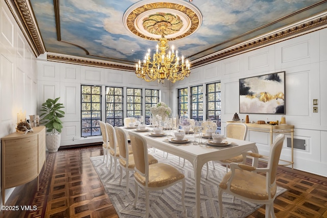 dining space with a decorative wall, a high ceiling, an inviting chandelier, and ornamental molding