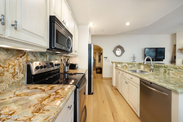627 Sawatch Dr Unit 302, Edwards, CO 81632 - kitchen featuring stainless steel appliances, light wood-type flooring, arched walkways, backsplash, and recessed lighting