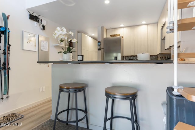 1552 Matterhorn Cir Unit 9, Vail, CO 81657 - kitchen featuring a breakfast bar area, light wood-style floors, dark countertops, recessed lighting, and baseboards