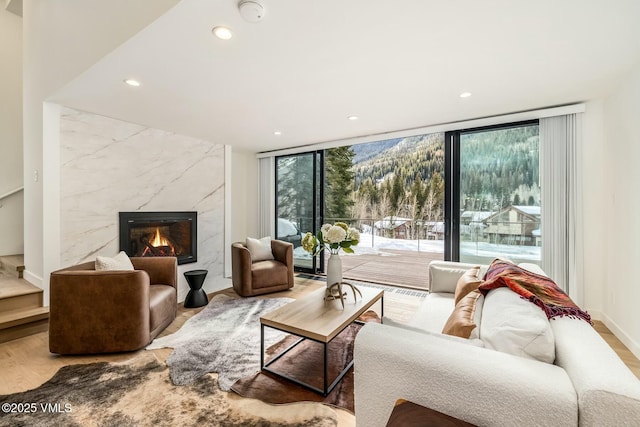 living room with floor to ceiling windows, recessed lighting, a premium fireplace, wood finished floors, and baseboards