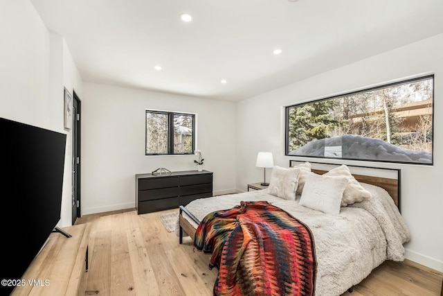 bedroom featuring baseboards, multiple windows, and light wood-style floors