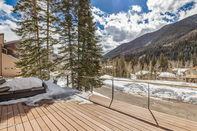 snow covered deck featuring a mountain view and a view of trees