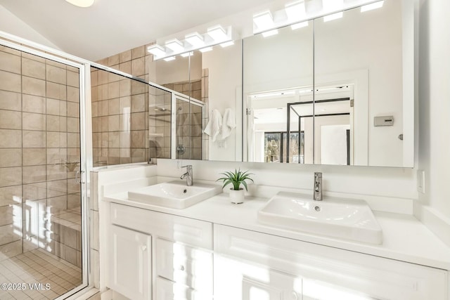 bathroom featuring a stall shower, a sink, and double vanity