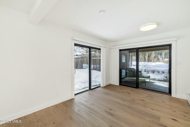 unfurnished room featuring a wealth of natural light, baseboards, and wood finished floors