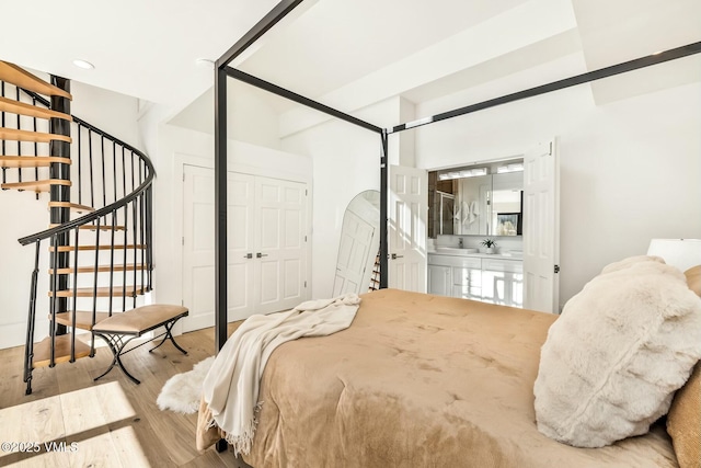 bedroom featuring ensuite bath and wood finished floors