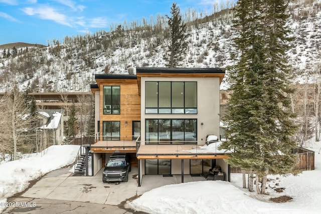 snow covered house with a patio and stairs