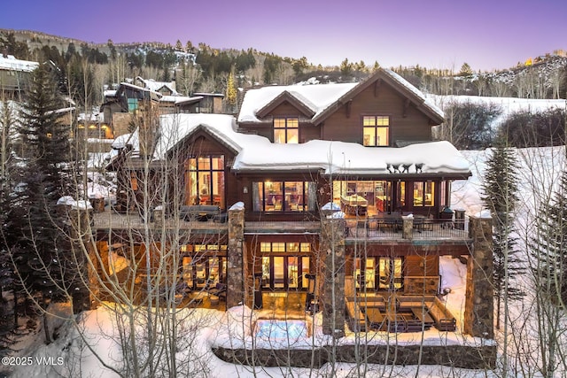 snow covered house featuring a balcony