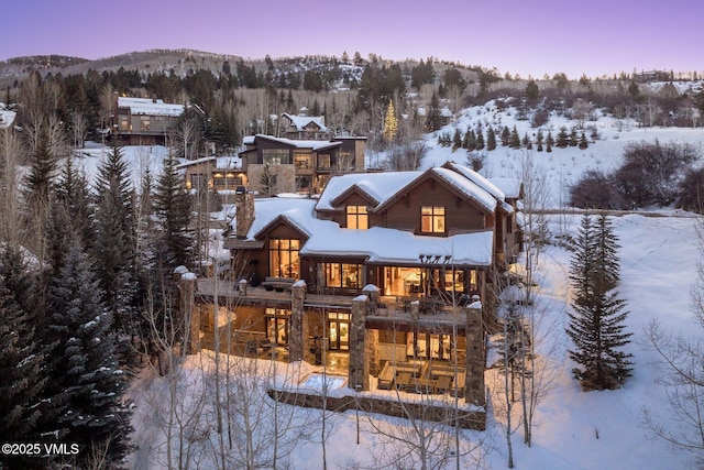 snow covered back of property featuring a mountain view