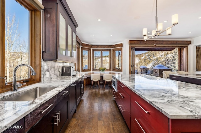 kitchen with light stone countertops, sink, and pendant lighting