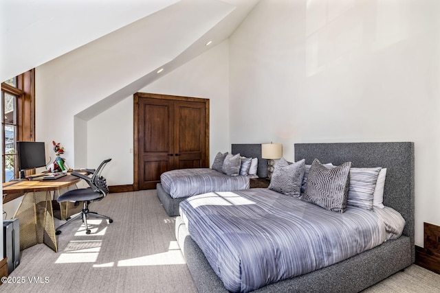 bedroom with high vaulted ceiling and light carpet