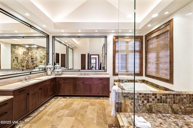 bathroom featuring a relaxing tiled tub, vanity, and lofted ceiling