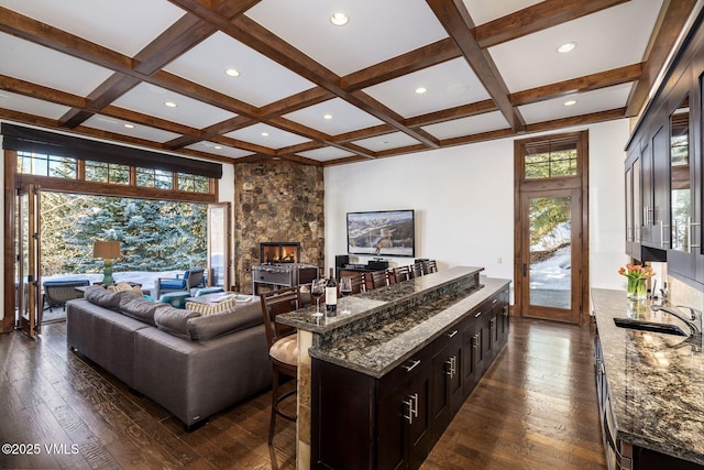 living room featuring coffered ceiling, dark wood-type flooring, and a healthy amount of sunlight