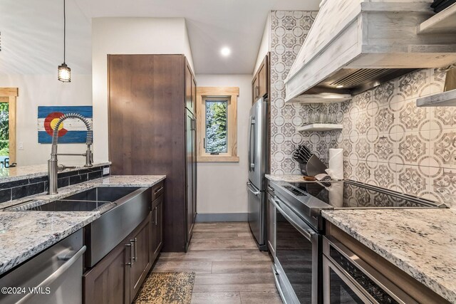 kitchen featuring custom exhaust hood, dark hardwood / wood-style floors, stainless steel appliances, light stone countertops, and decorative backsplash