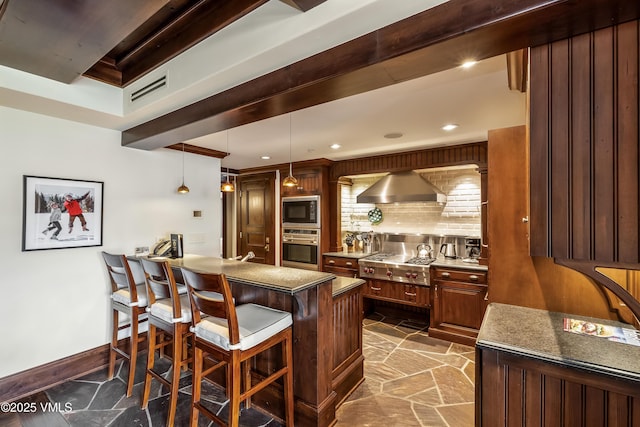 1 Willow Bridge Rd Unit 36, Vail, CO 81657 - bar area featuring stainless steel appliances, dark stone finish flooring, wall chimney exhaust hood, decorative light fixtures, and baseboards