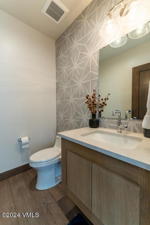 bathroom with wood-type flooring, toilet, and vanity