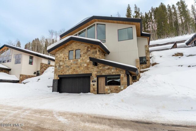 snow covered rear of property featuring a garage