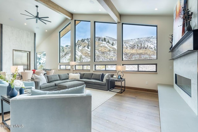 living room featuring high vaulted ceiling, a fireplace, beamed ceiling, a mountain view, and light hardwood / wood-style flooring