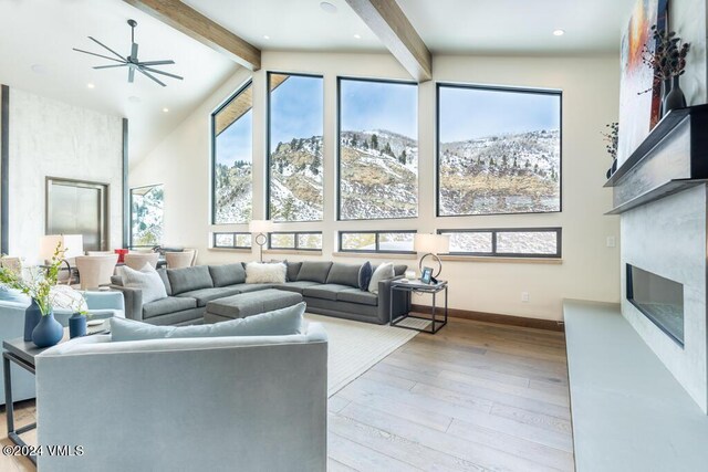 living room with ceiling fan, beam ceiling, high vaulted ceiling, a mountain view, and light wood-type flooring