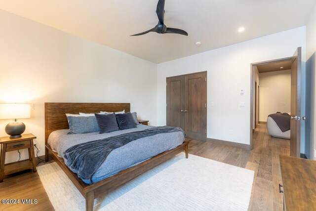 bedroom with hardwood / wood-style flooring, ceiling fan, and a closet