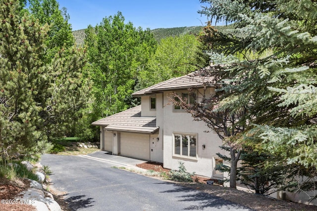 220 Singletree Rd, Edwards, CO 81632 - view of front facade featuring stucco siding, asphalt driveway, and a forest view