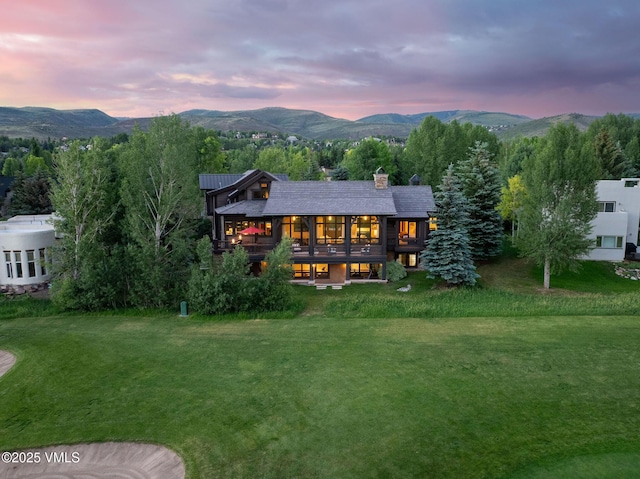 44 Conestoga Cir, Edwards, CO 81632 - back of property at dusk with a lawn, a mountain view, a chimney, and a balcony