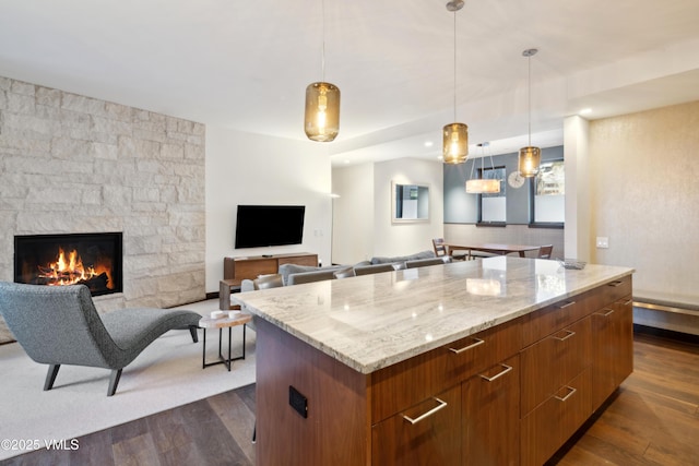 kitchen with modern cabinets, dark wood-style floors, light stone countertops, and a center island