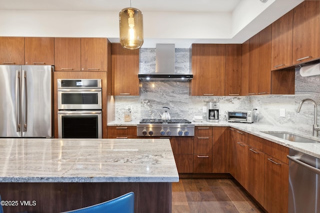 kitchen featuring a sink, light stone counters, backsplash, stainless steel appliances, and wall chimney exhaust hood