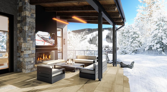 snow covered patio featuring a mountain view and an outdoor living space with a fireplace